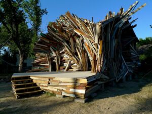 Artistic structure made from wooden planks and beams arranged in a swirling pattern.