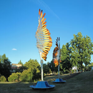 Image of two freestanding sculptures with protruding feather-like structures in yellow and orange at the top
