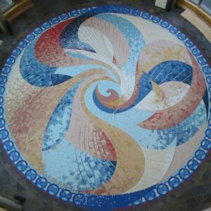 Image of circular terrazzo floor from aerial perspective. Blue border with interlacing spiral details in beige, blue and red.